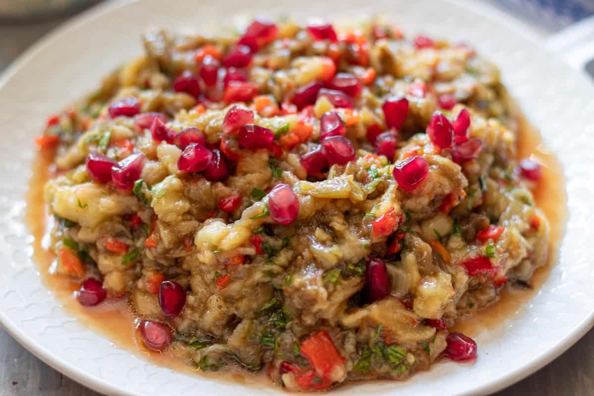Chunky eggplant dip in a serving bowl with parsley and pomegranate seeds