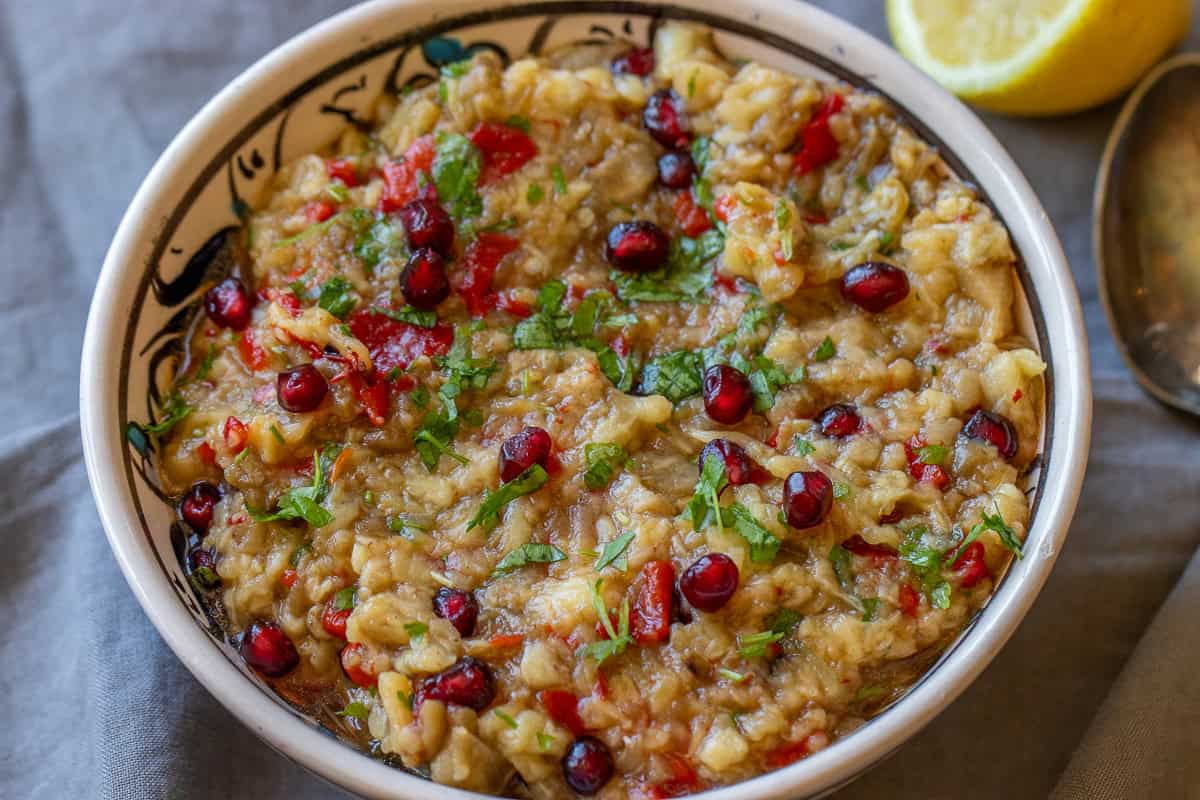 Baba ganoush without tahini topped with pomegranate seeds, parsley, and olive oil