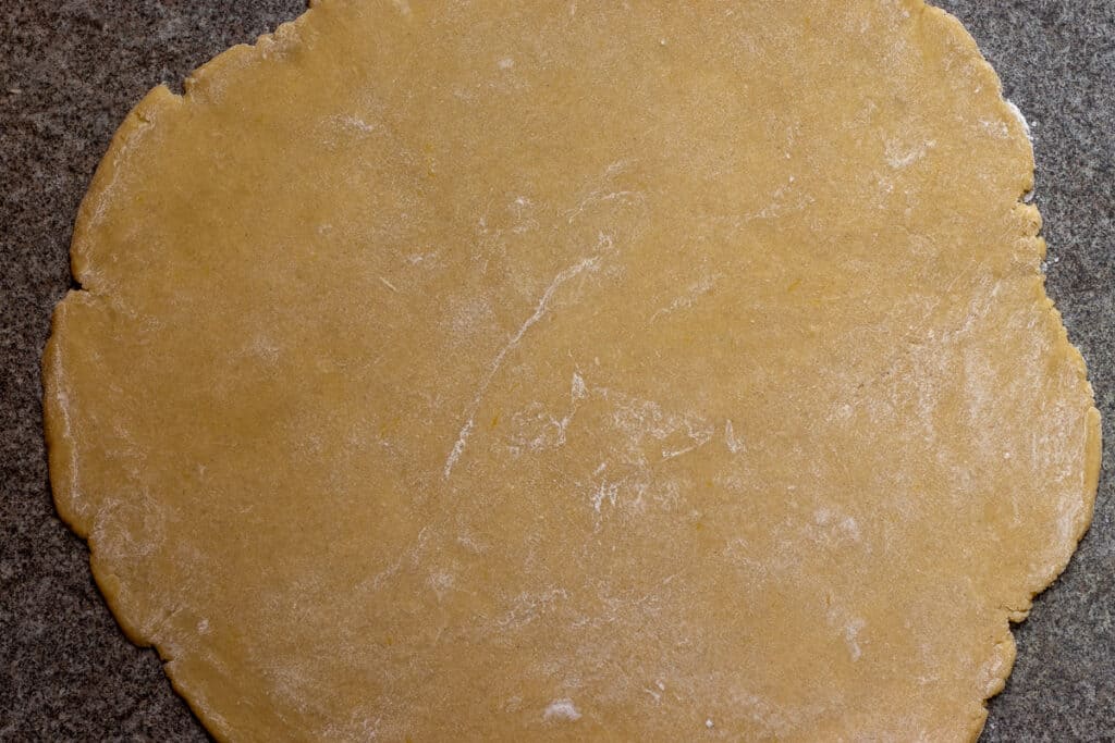 The tartlet dough rolled out between two sheets of baking paper.