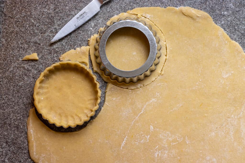 Ten rounds cut from the rolled tartlet dough.