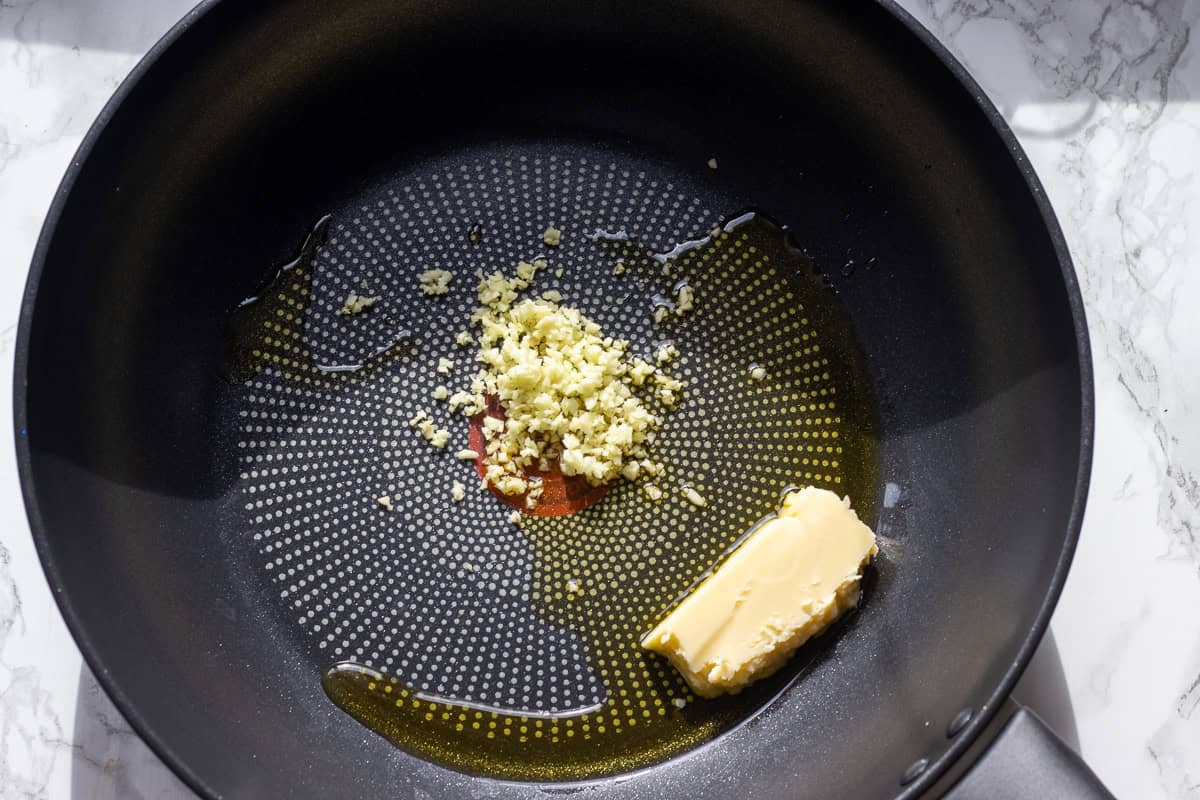 Butter, olive oil, and chopped garlic are placed in a pan.