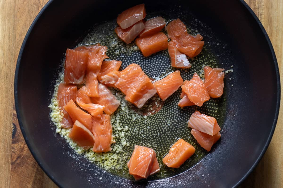 Lightly cooking salmon pieces in oil and butter.