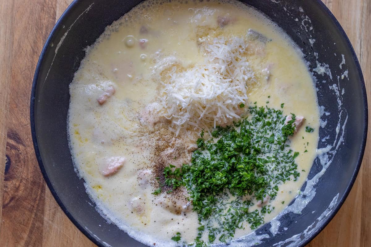 Parmesan, seasoning, and herbs are added to the creamy sauce.