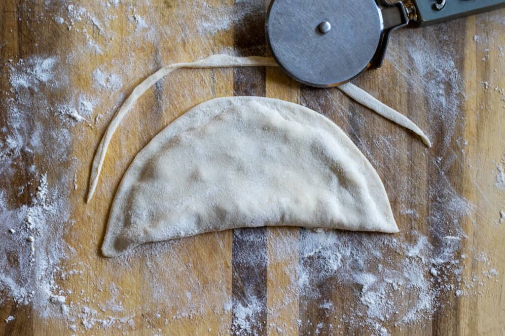 The sides of the pastry are trimmed with a pizza cutter.