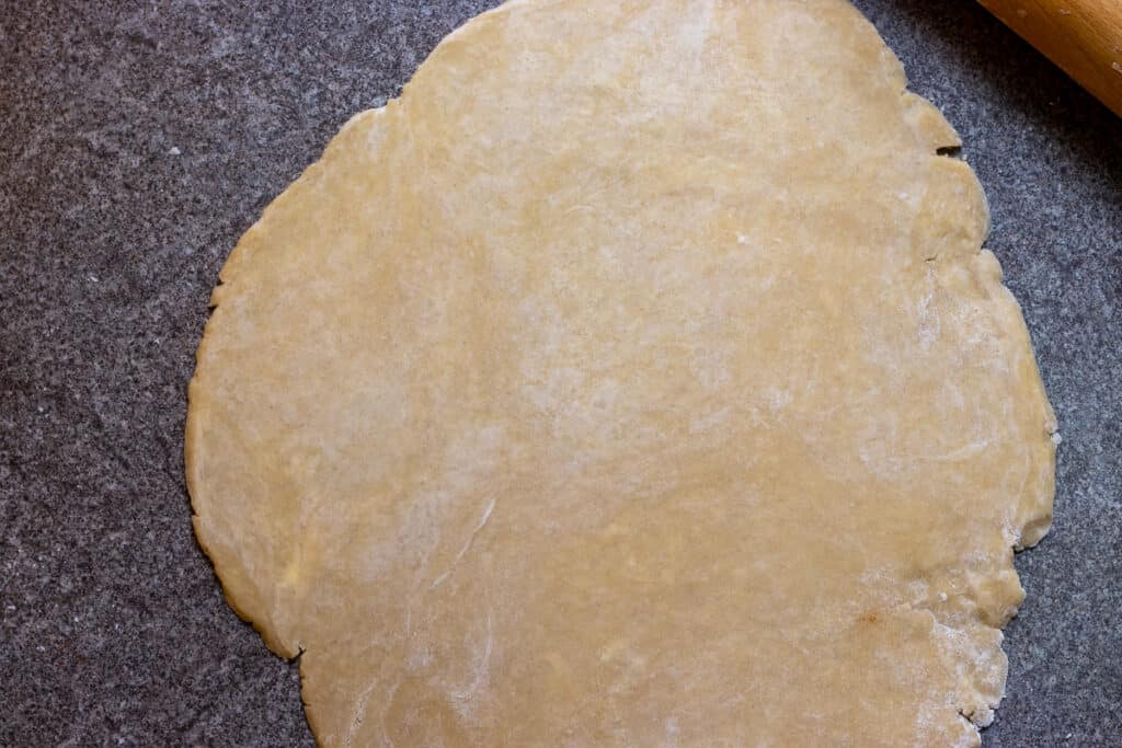 Quiche dough is rolled out into a circle.