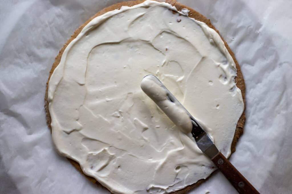 Spreading frosting on top of a cake layer.