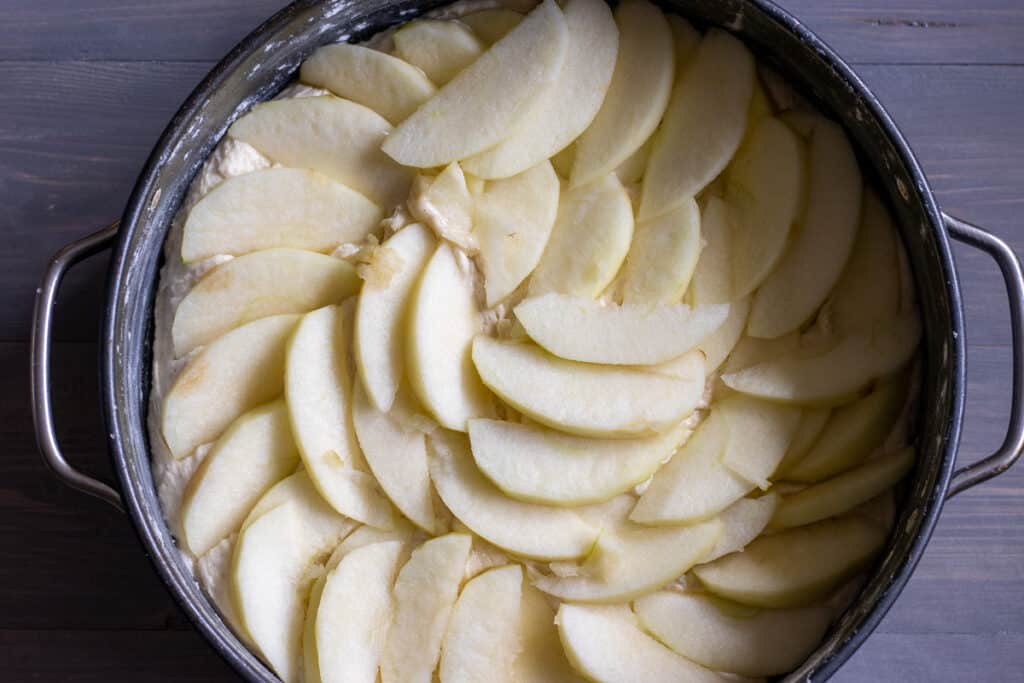 Sliced apples are scattered on top of the cake batter.