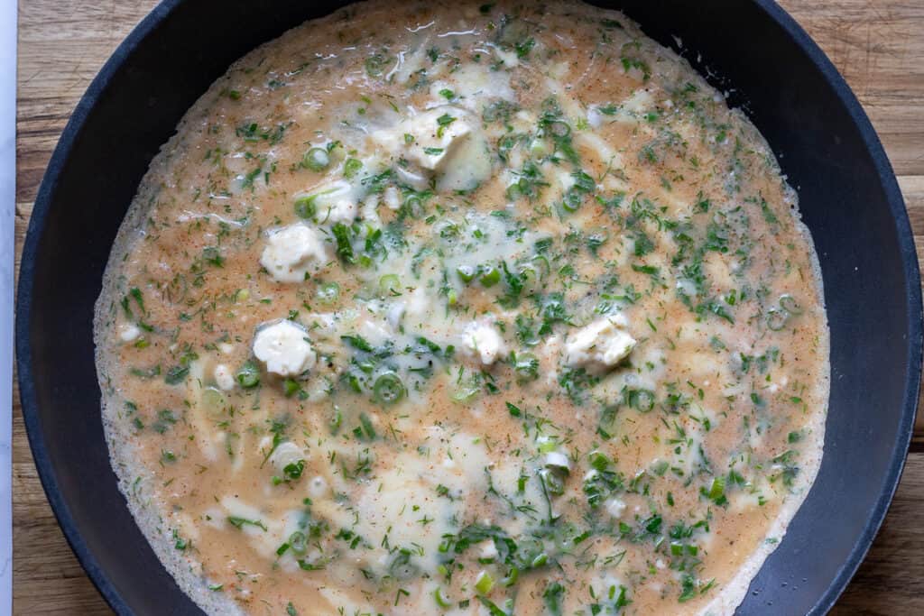 A ladle of the batter poured into a hot pan.
