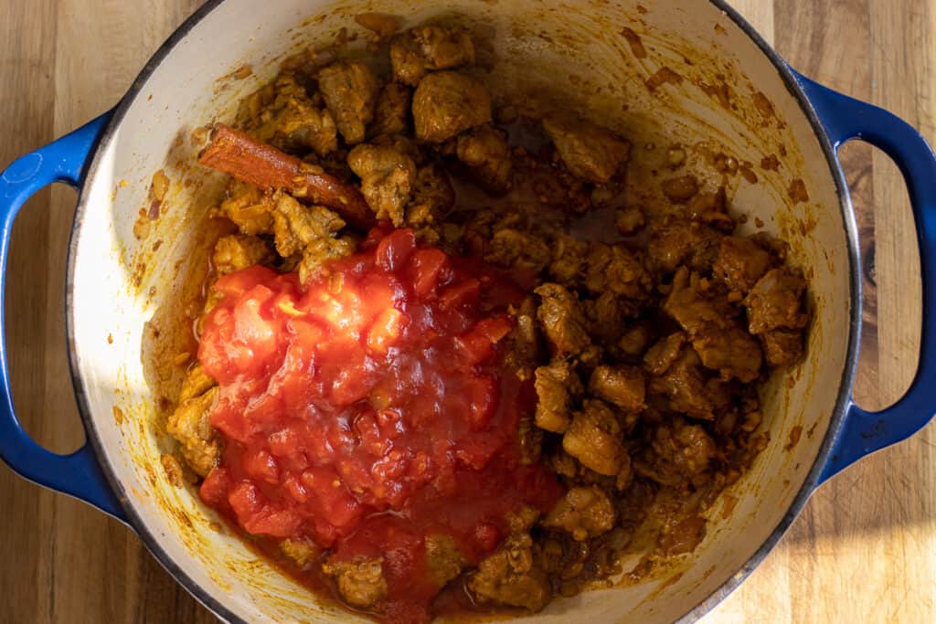 Canned tomatoes added to the Dutch oven.