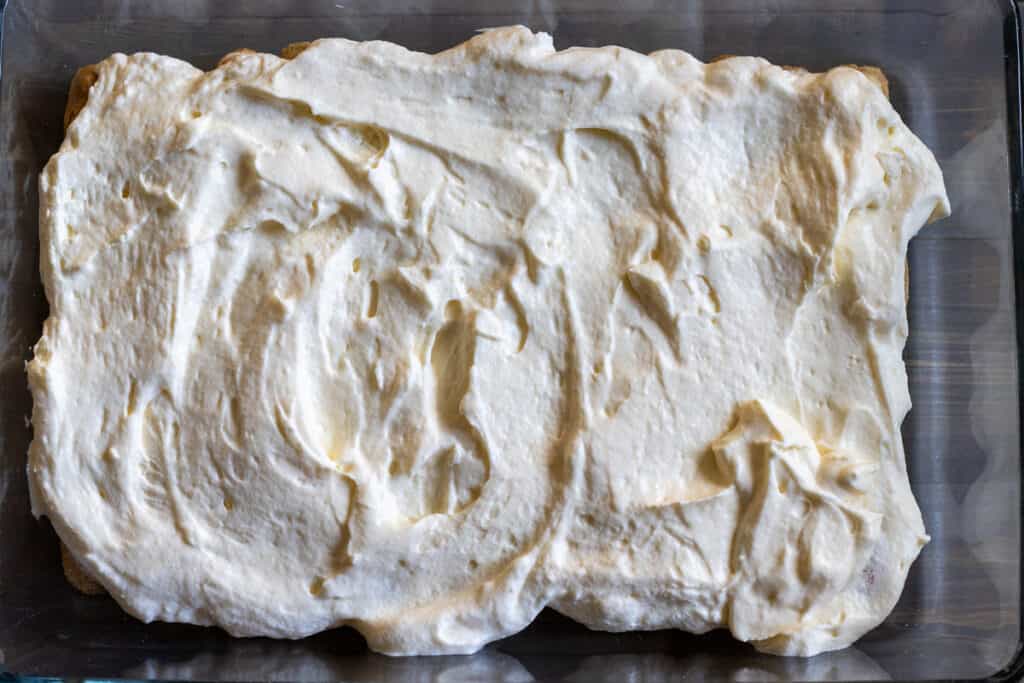 Half of the mascarpone filling spread over the ladyfingers.