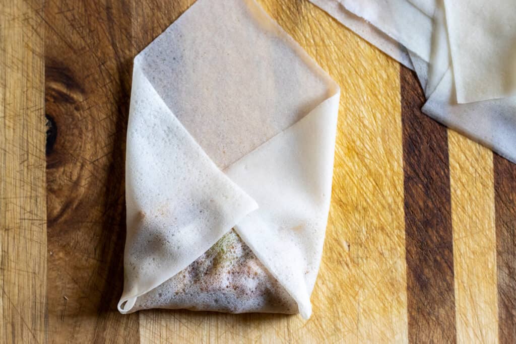 The sides of a spring roll wrapper folded over the duck filling.