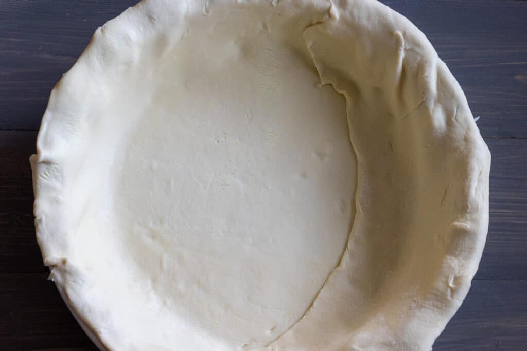 The puff pastry is rolled out and placed in a pie dish.