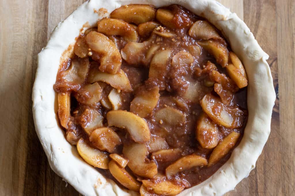 The apple filling is placed in pie dish over the dough.