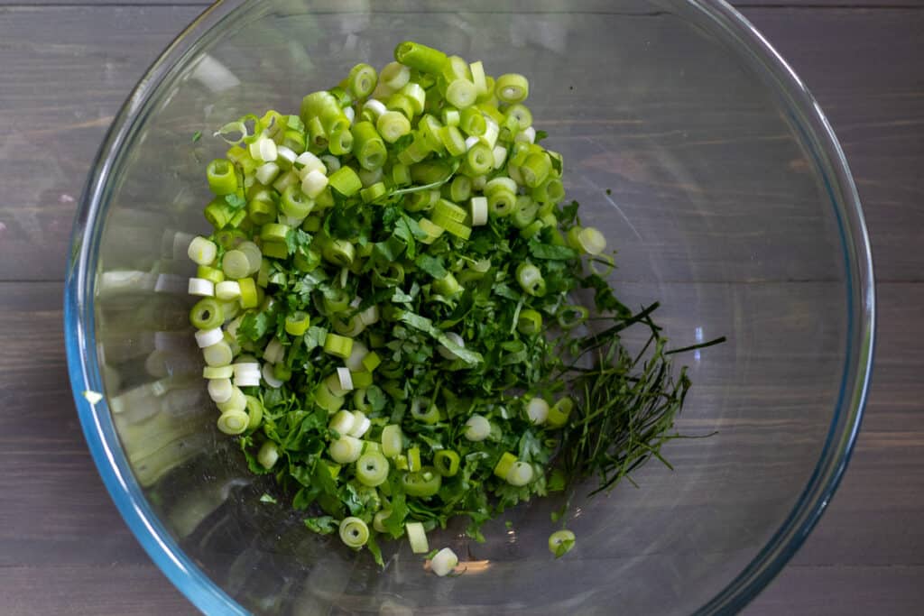 Lemongrass, lime leaves, coriander, and spring onions in a bowl.