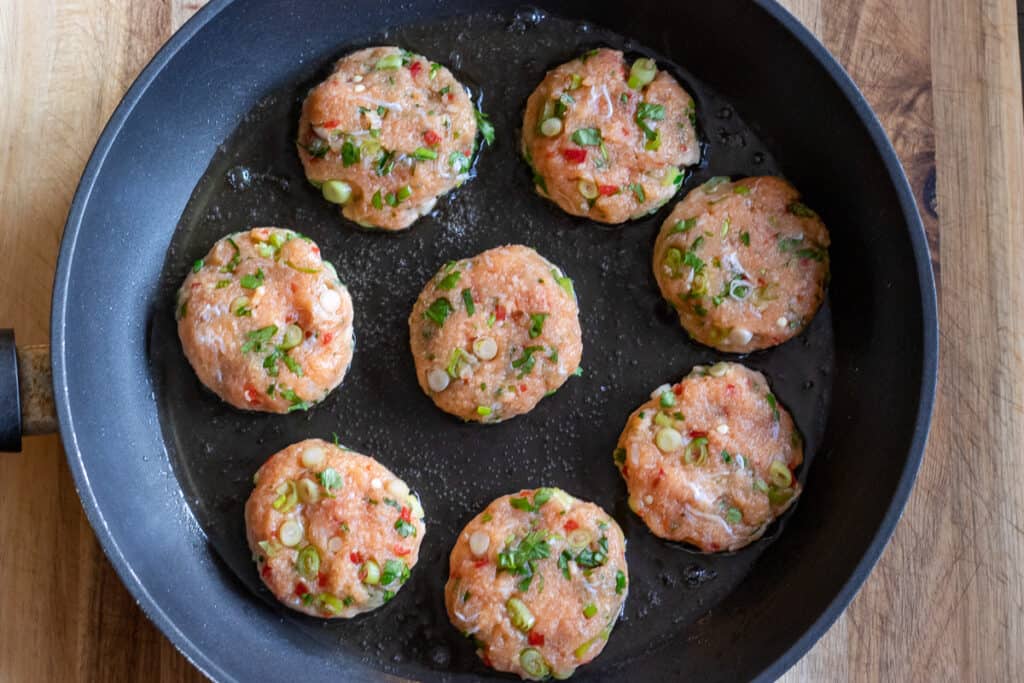 Fish cakes frying in a pan of oil.