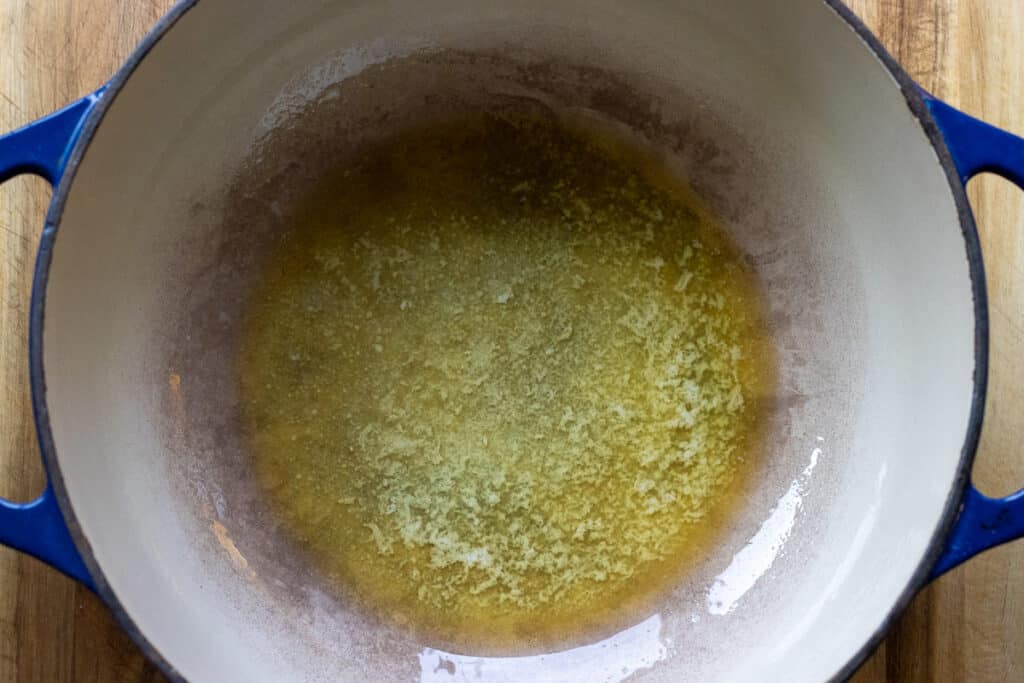 Melted butter in a blue Dutch oven, ready for the onions.