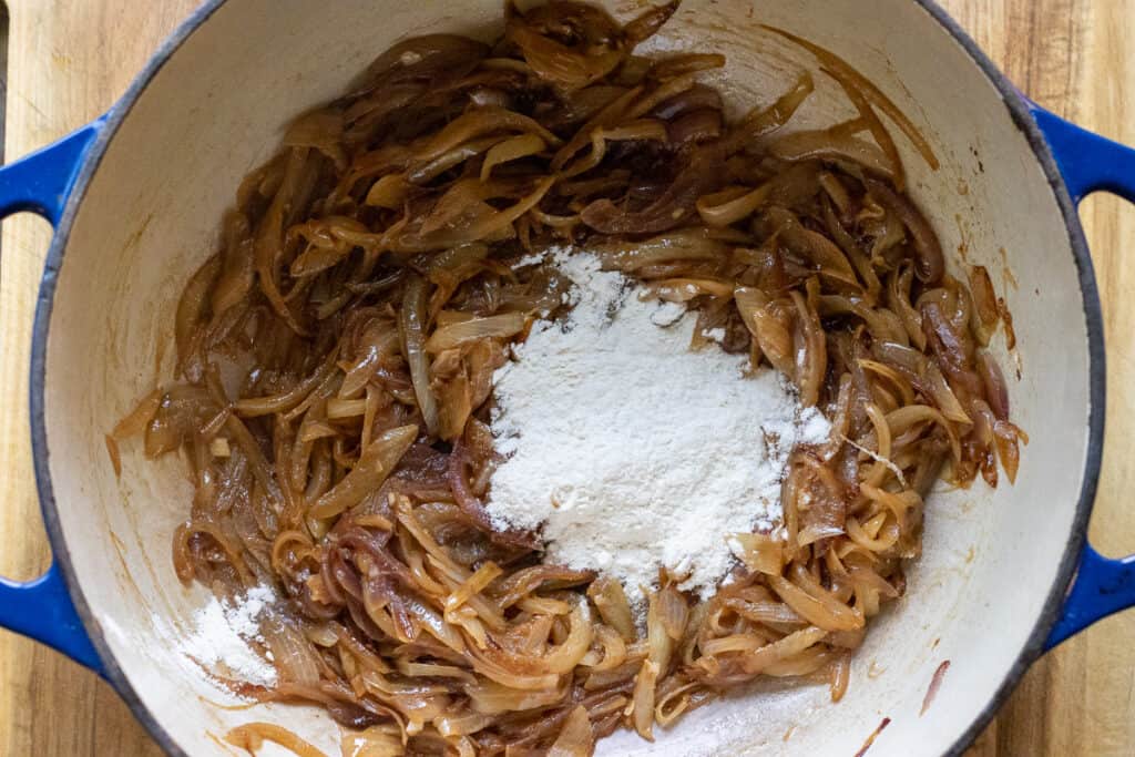 Flour sprinkled over the caramelized onions in the pot.