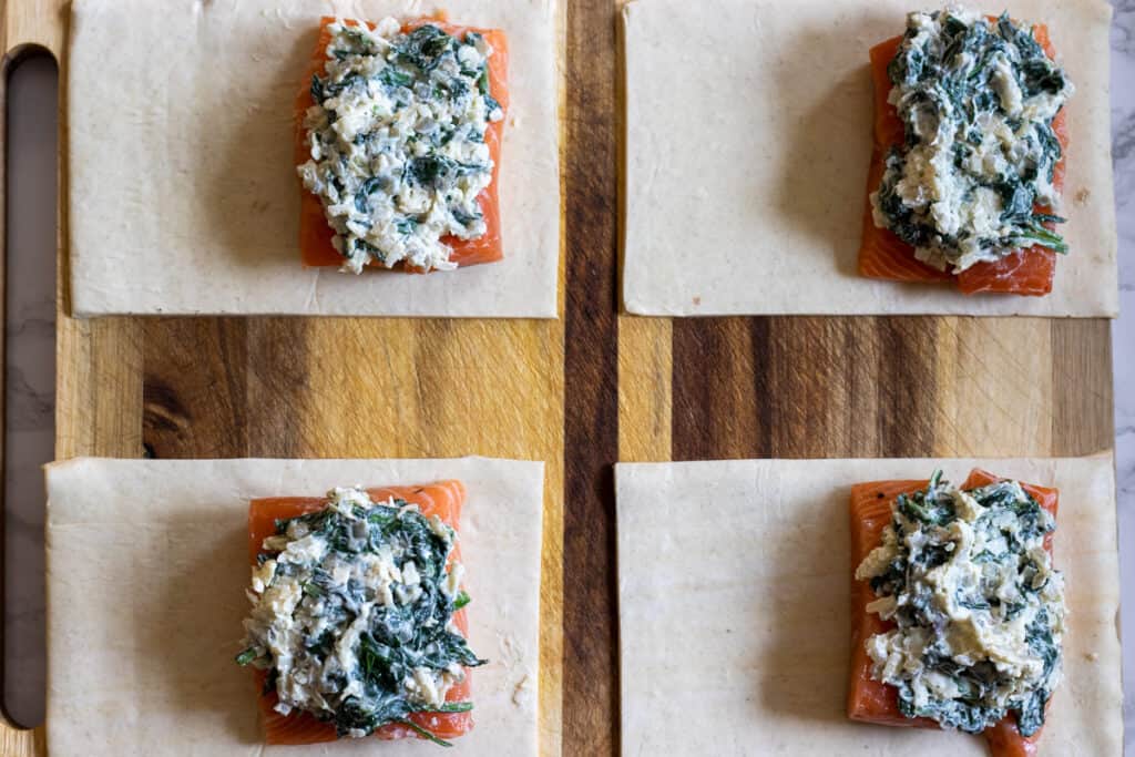 Spinach filling is spooned out on salmon fillets.