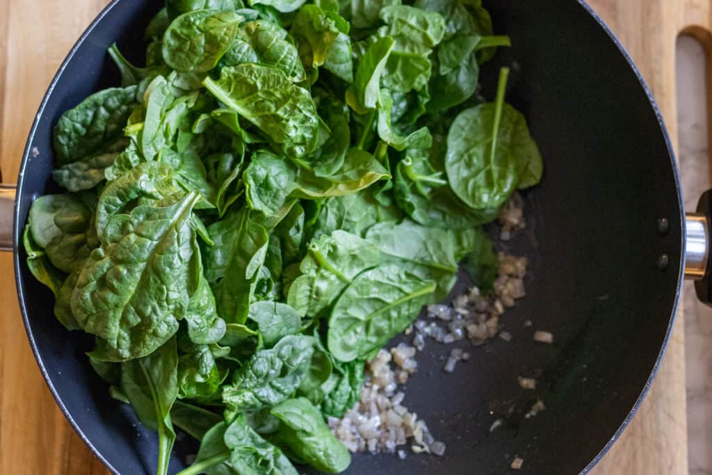 Fresh spinach leaves are added to the pan.