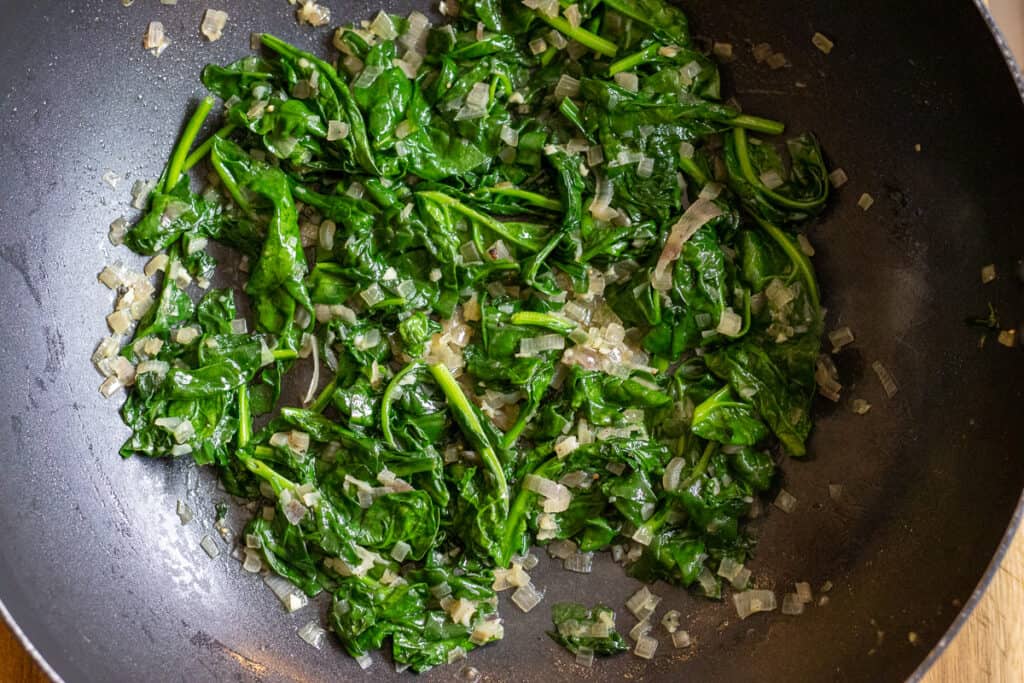 The spinach is sautéed with onions and garlic.