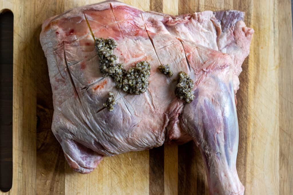 The spice mixture being rubbed onto the lamb shoulder.