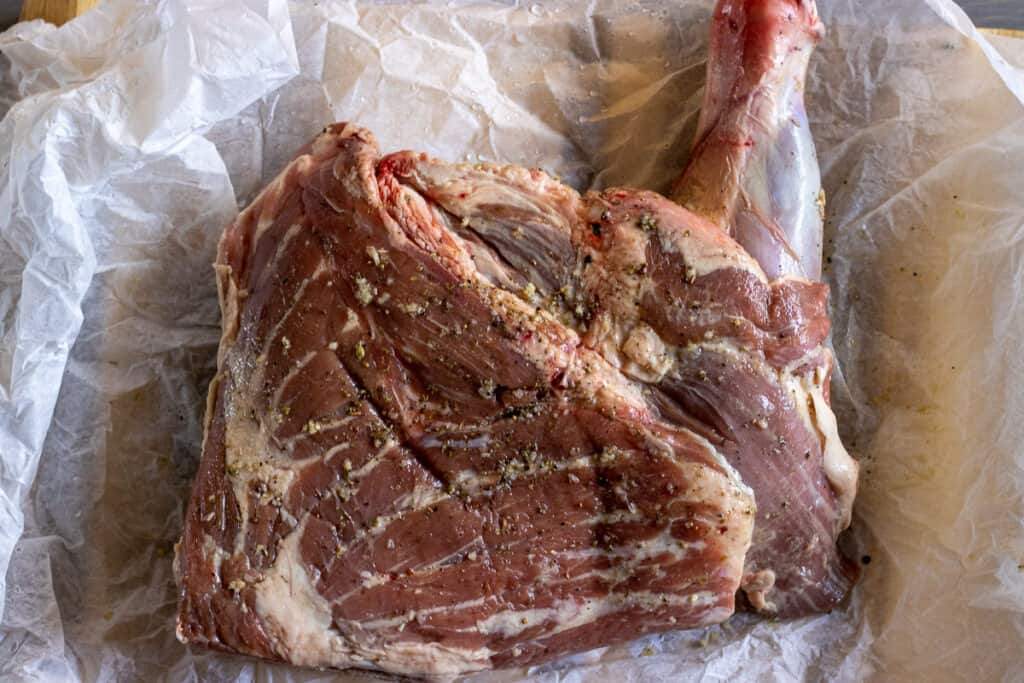 Lamb shoulder placed on a large sheet of parchment paper.
