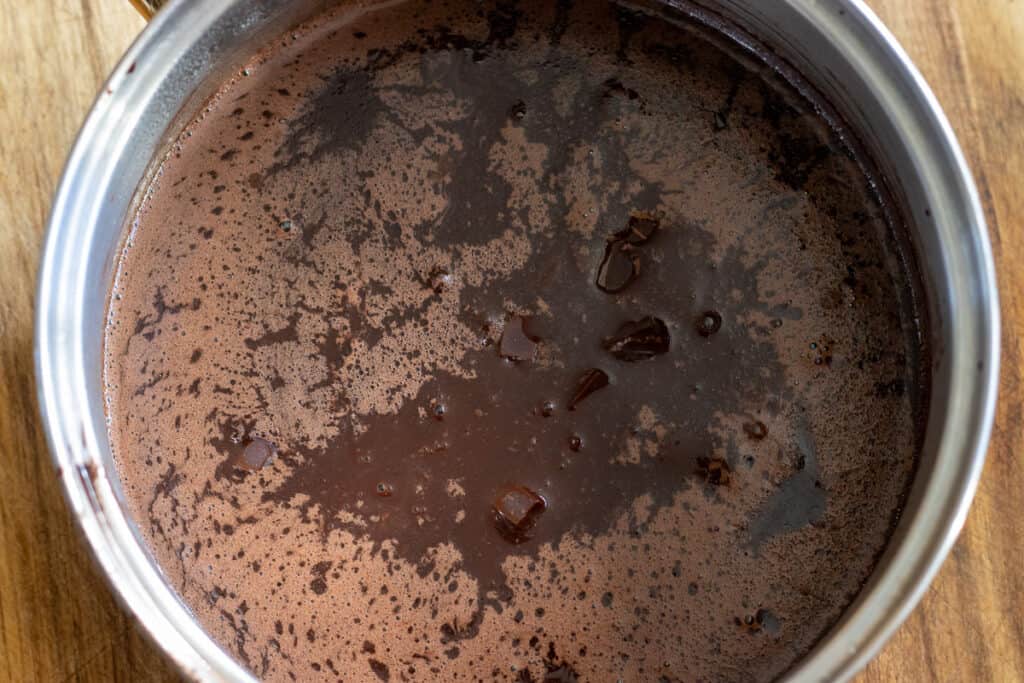 Chocolate pieces are added to the hot milk and cocoa mixture.