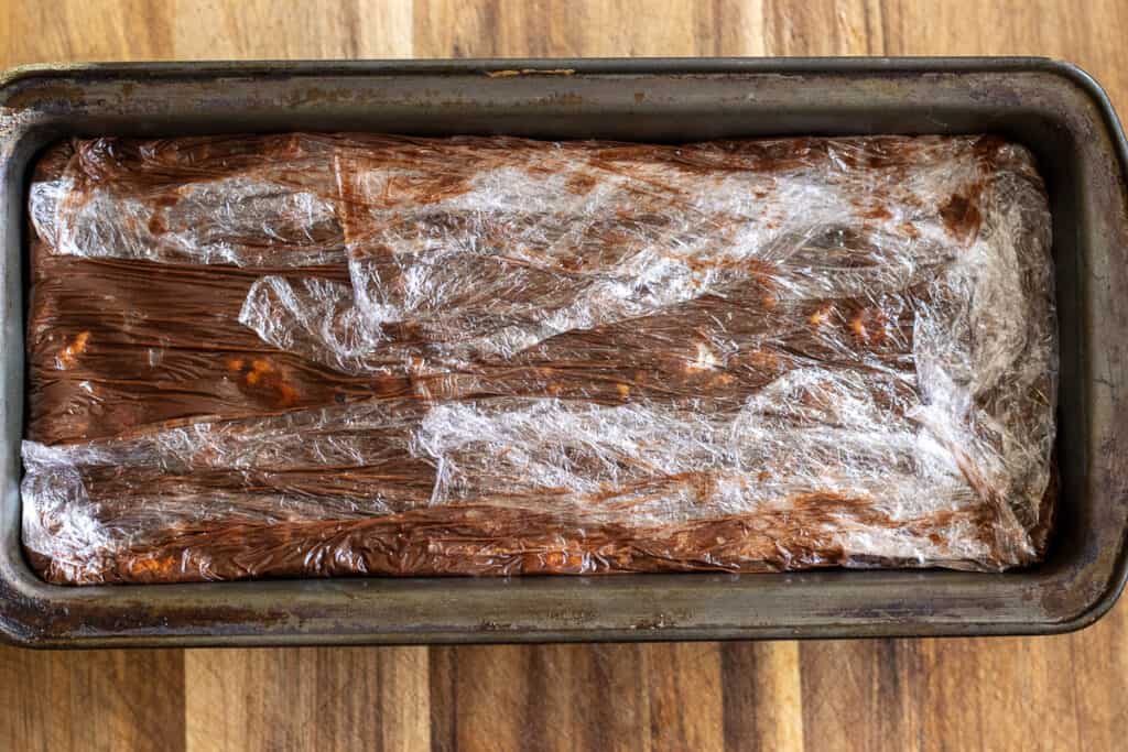 The cake is covered with overhanging cling film.