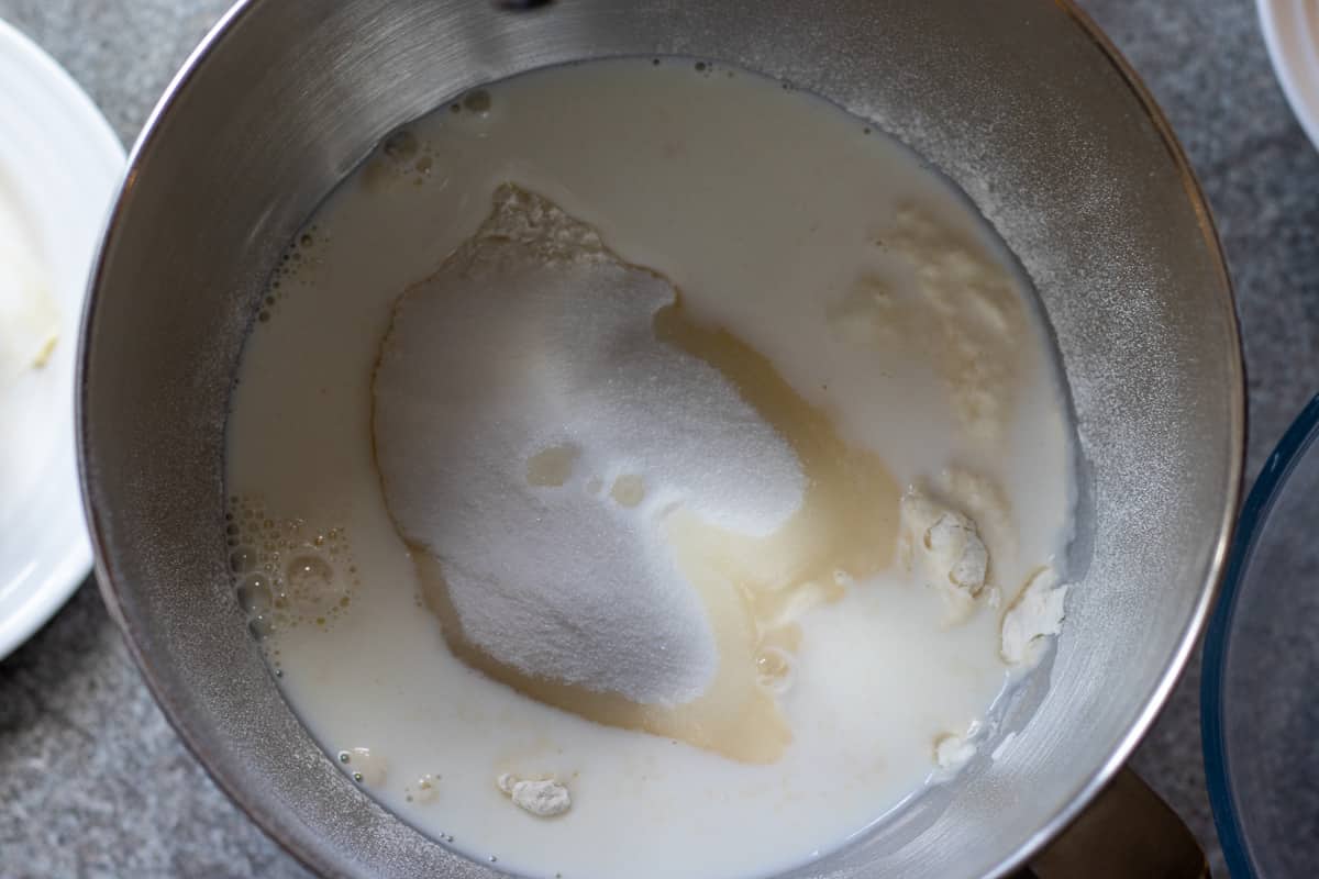 Milk, sugar, yeast, salt, and flour in a mixing bowl.