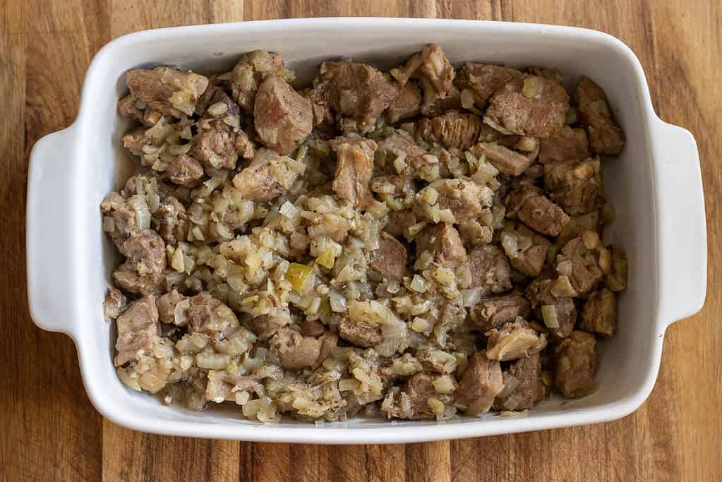 The tender lamb meat is transferred to a baking dish.