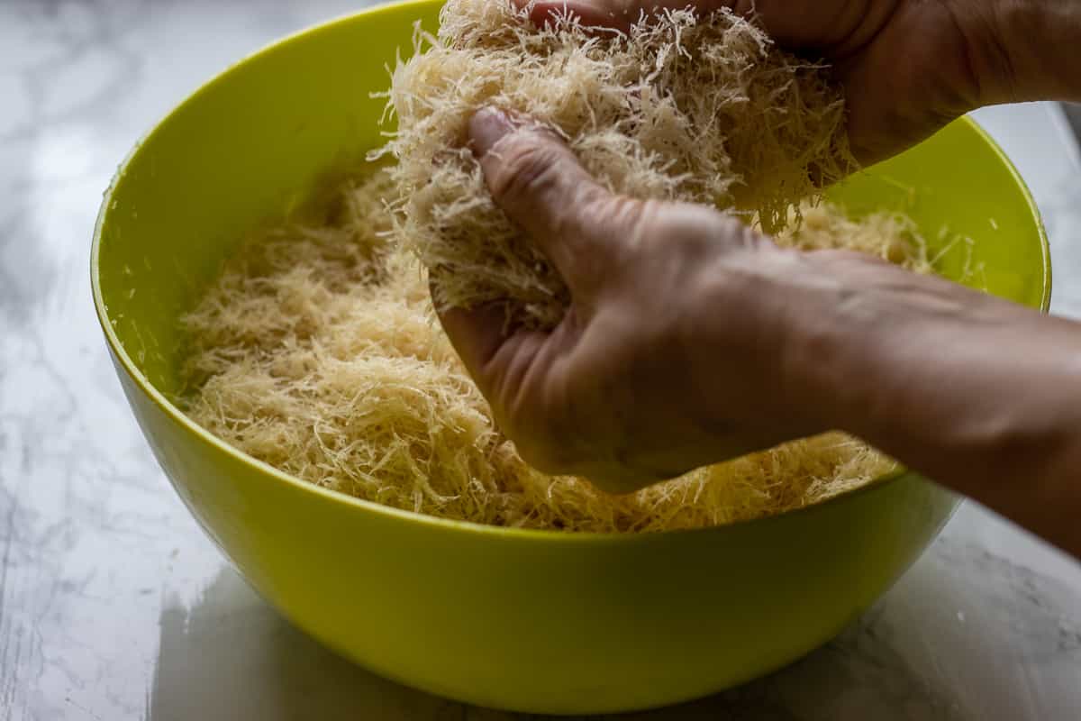 Coating the kadaif pastry with butter.