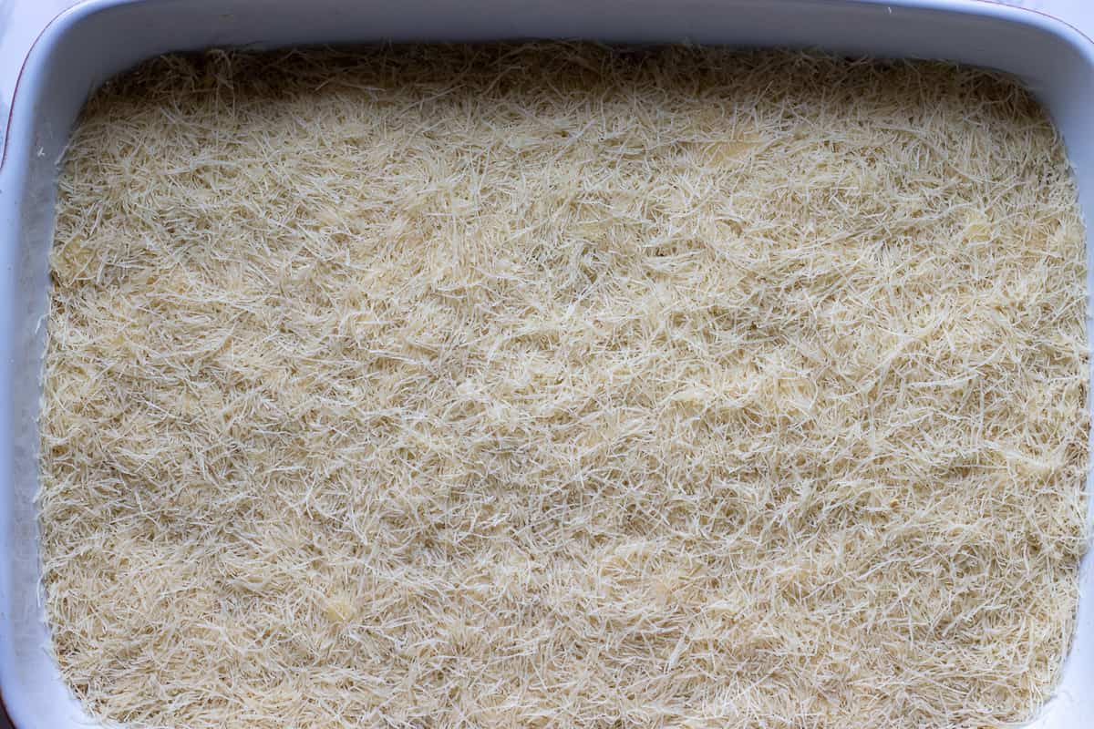 The second layer of pastry strands is placed over the walnut filling.