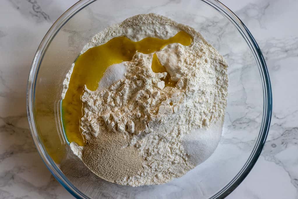 Flour, olive oil, salt, sugar and yeast in a glass bowl.