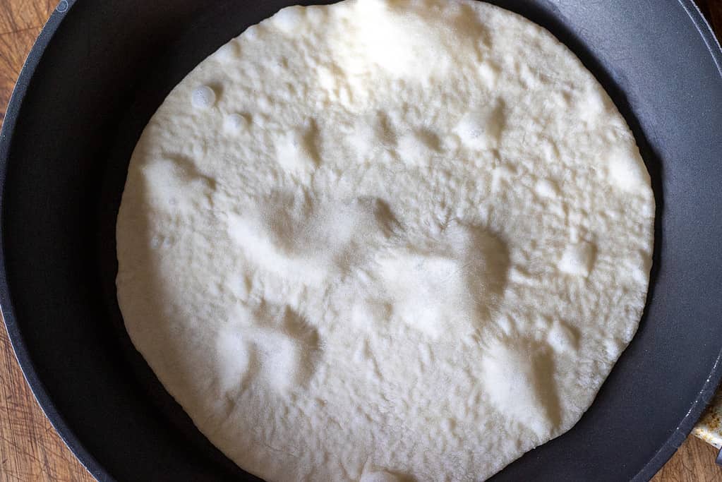 A dough circle is placed in a hot pan.
