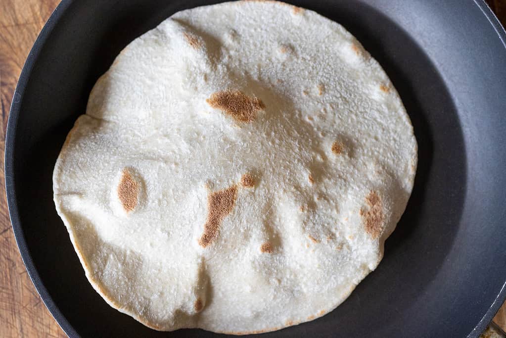 The dough circle is flipped to cook the other side.