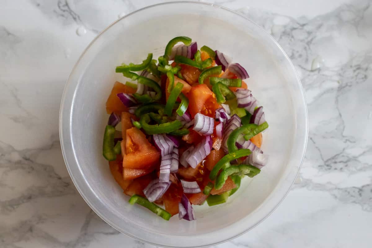 Sliced green pepper and diced red onion on top of the tomatoes and cucumbers.