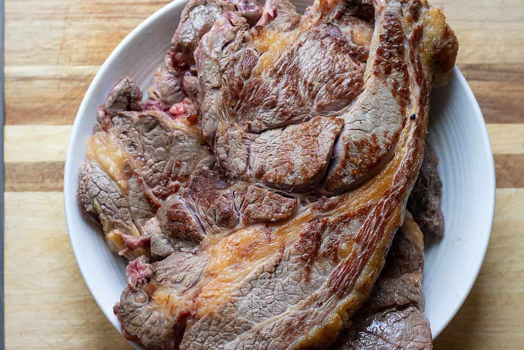 Seared chuck roast is set aside on a plate.