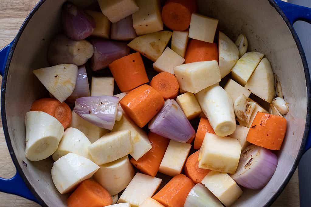 Chopped vegetables are added to the Dutch oven.