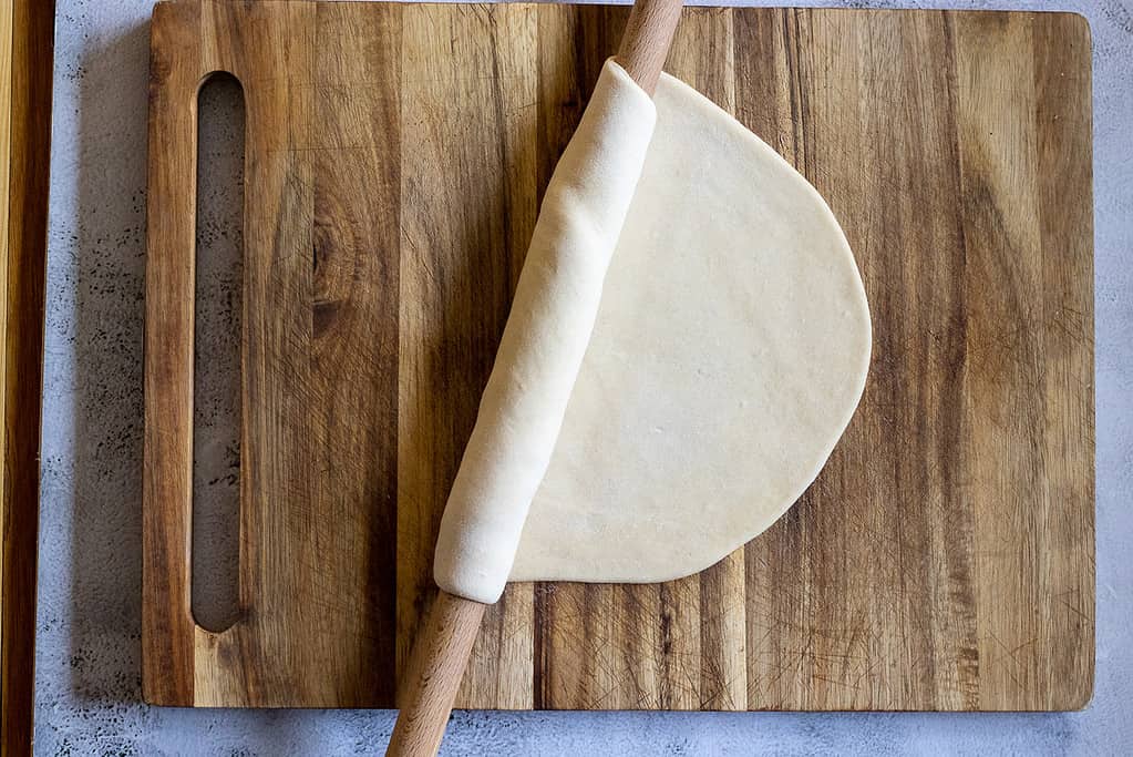Rolling out a dough ball using a thin rolling pin.