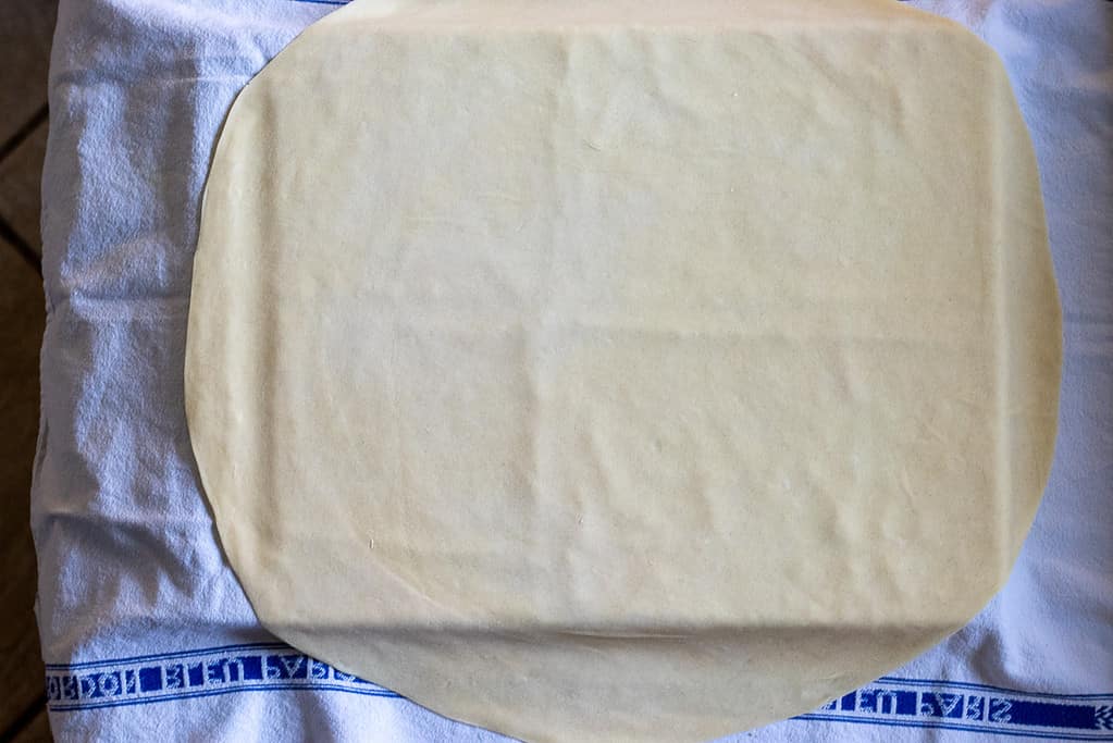 The dough rolled out into a large, thin circle.