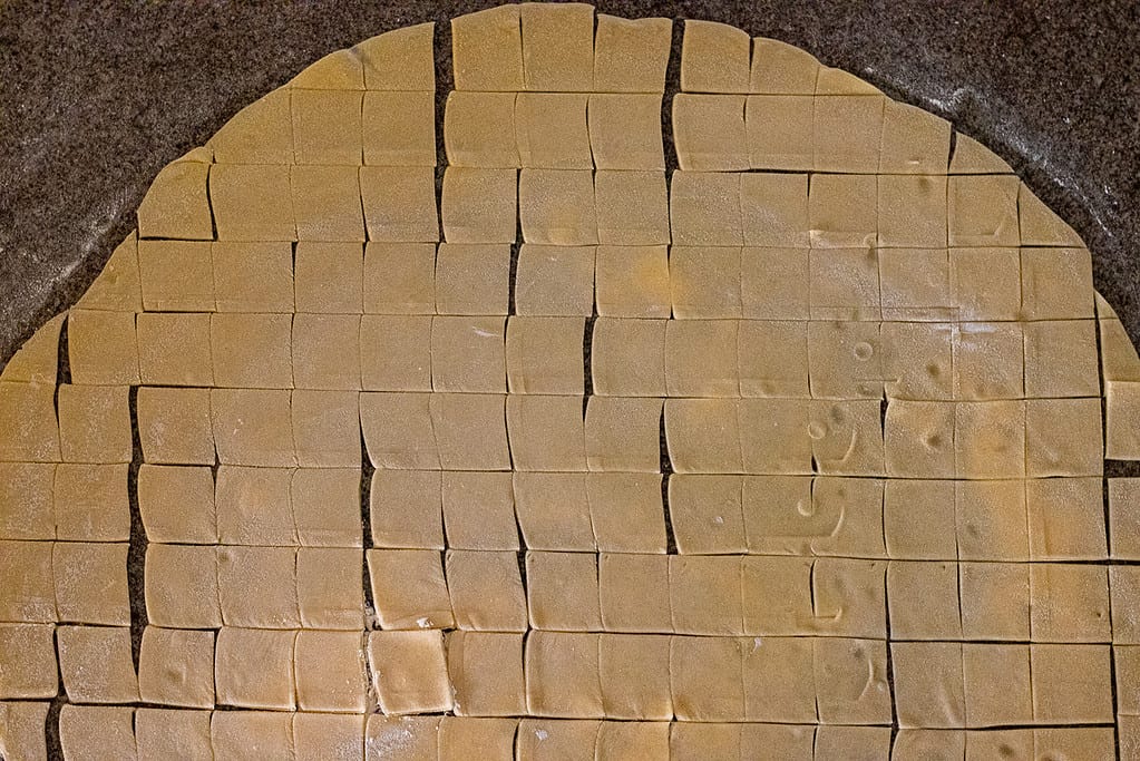 The dough circle cut into small 3 cm squares.