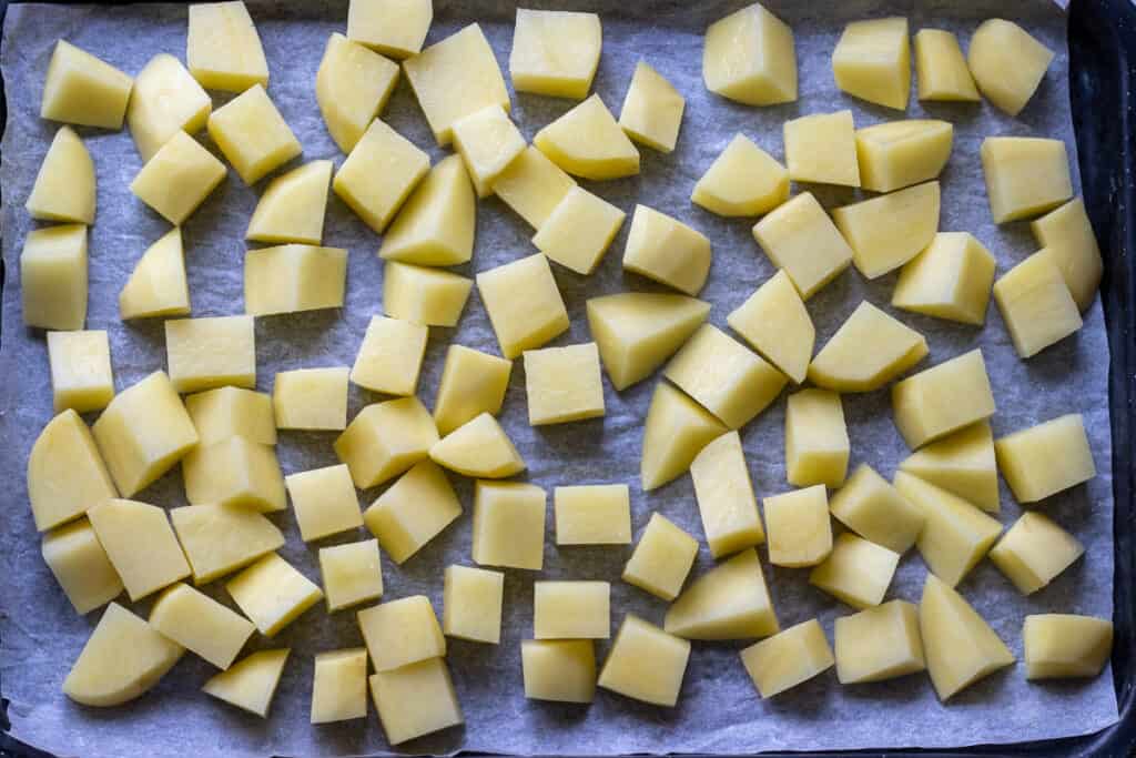 Potato cubes are placed on a baking sheet.