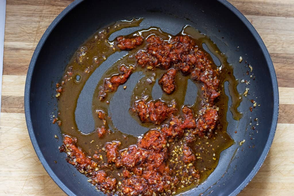 Red pepper paste, black pepper, and salt are added to the sautéed garlic.