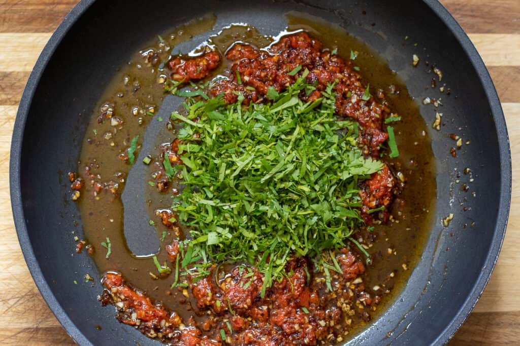 Chopped cilantro is added to the sauce.