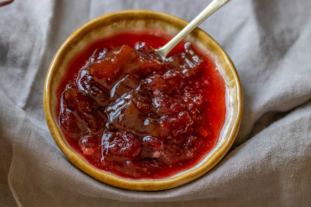 Jam in a small bowl with a small spoon in it.
