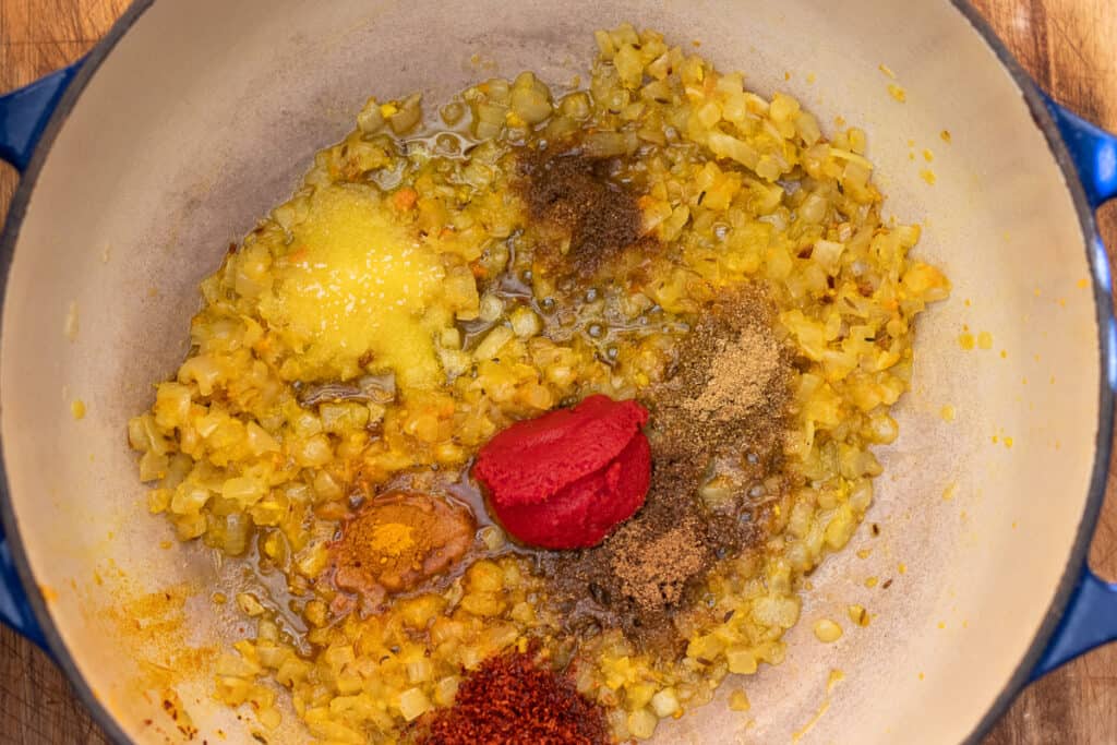 Ground spices and tomato paste stirred into the onions.