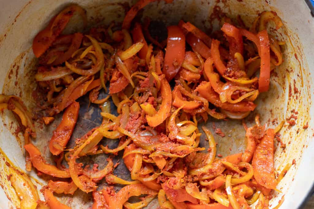 Tomato paste and spices are added to sautéed vegetables.