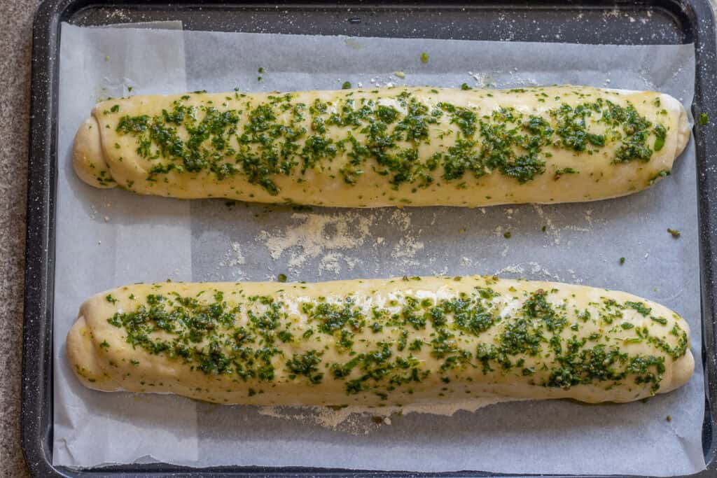 2 bread loaves brushed with an herb and olive oil mixture.