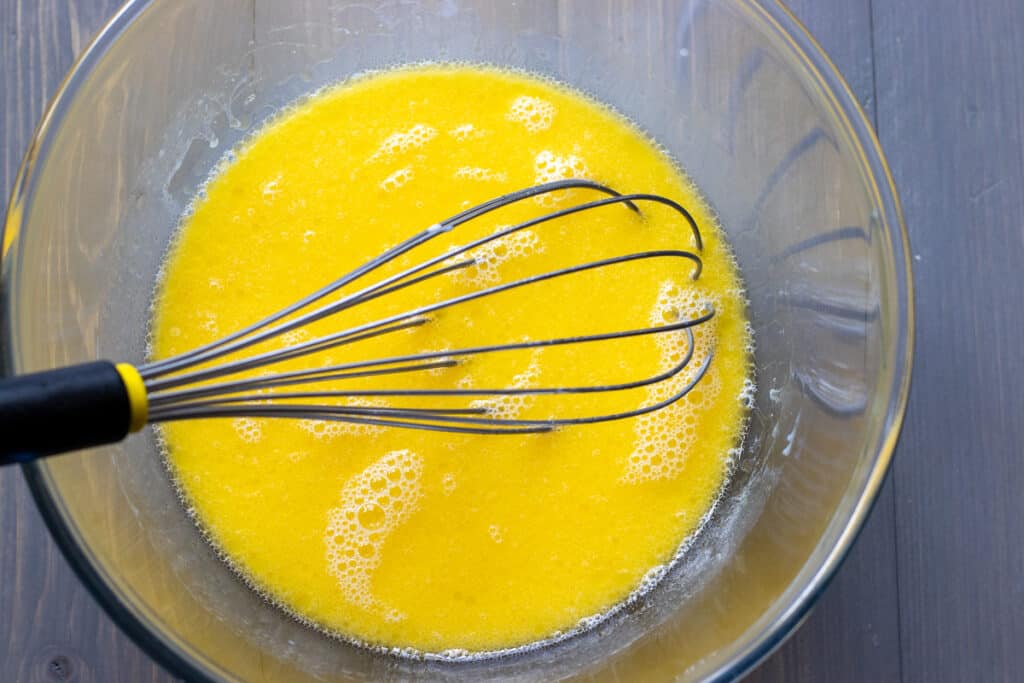 Melted butter, eggs, and milk whisked together in a bowl.