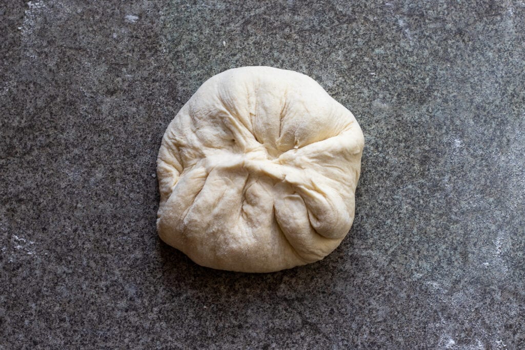 The stuffed dough circle is shaped into a ball.